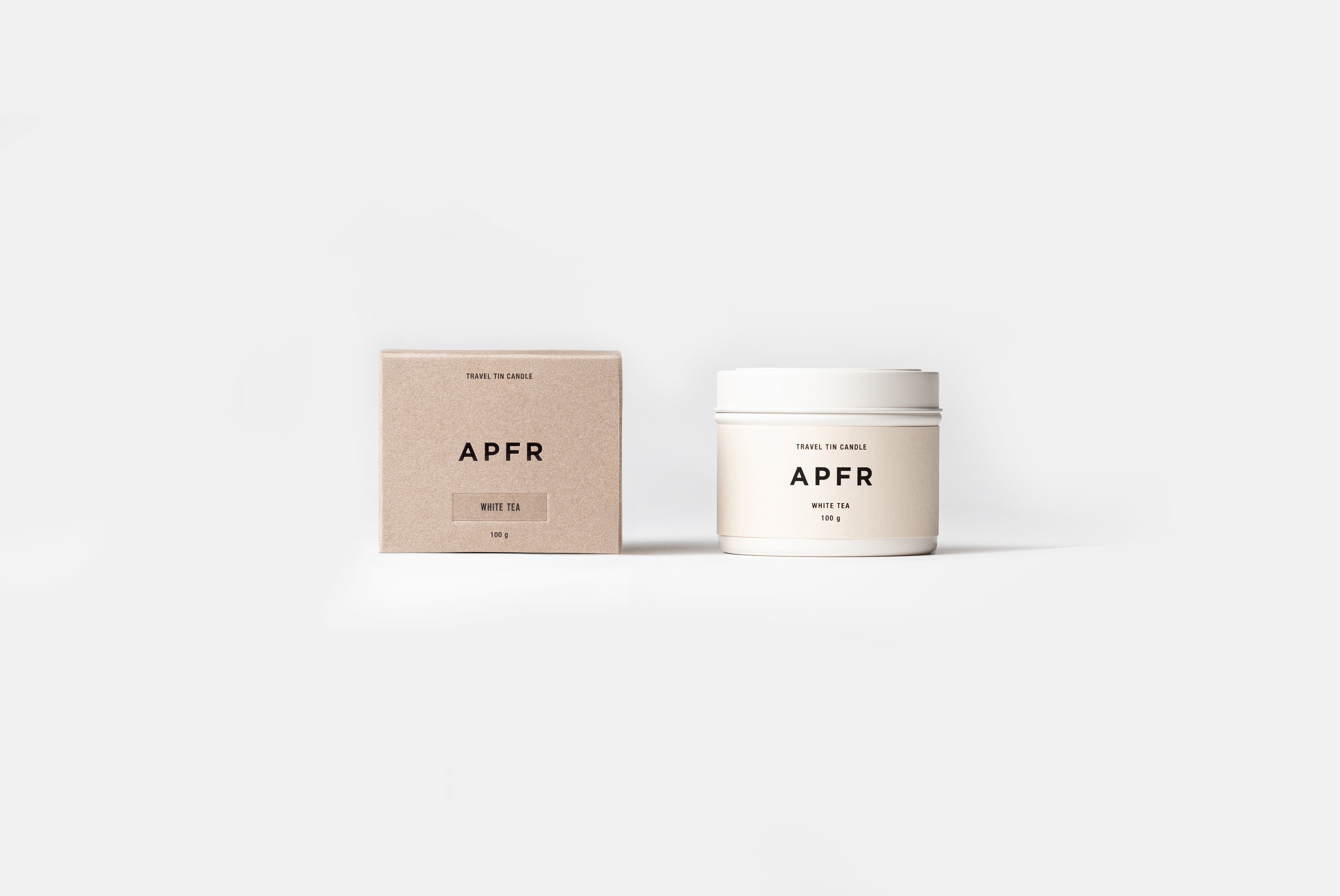 APFR Travel Tin Candle in White Tea scent, shown next to packaging on white background