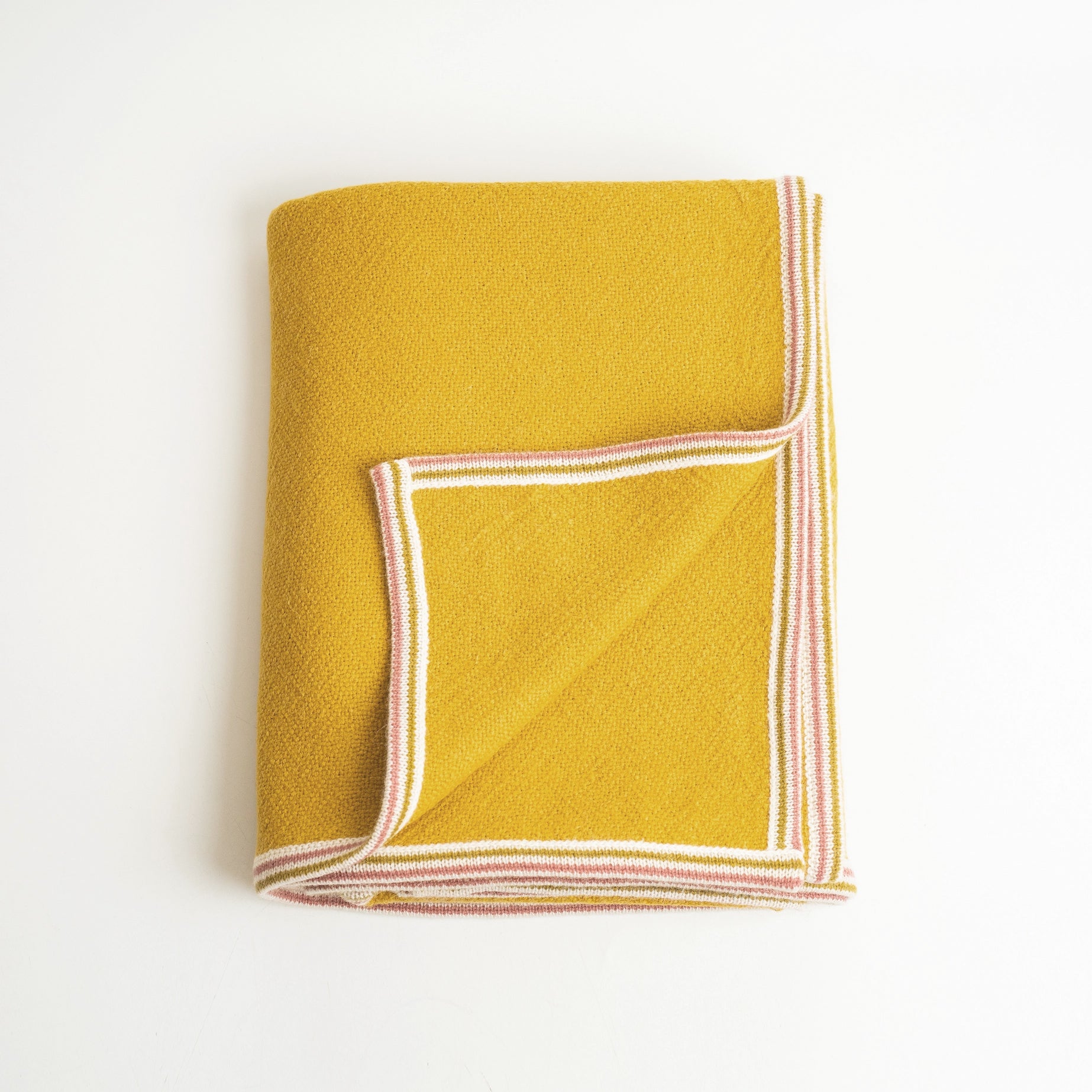 Alpaca Wool blanket in Citrine color shown folded with corner flipped up on white background