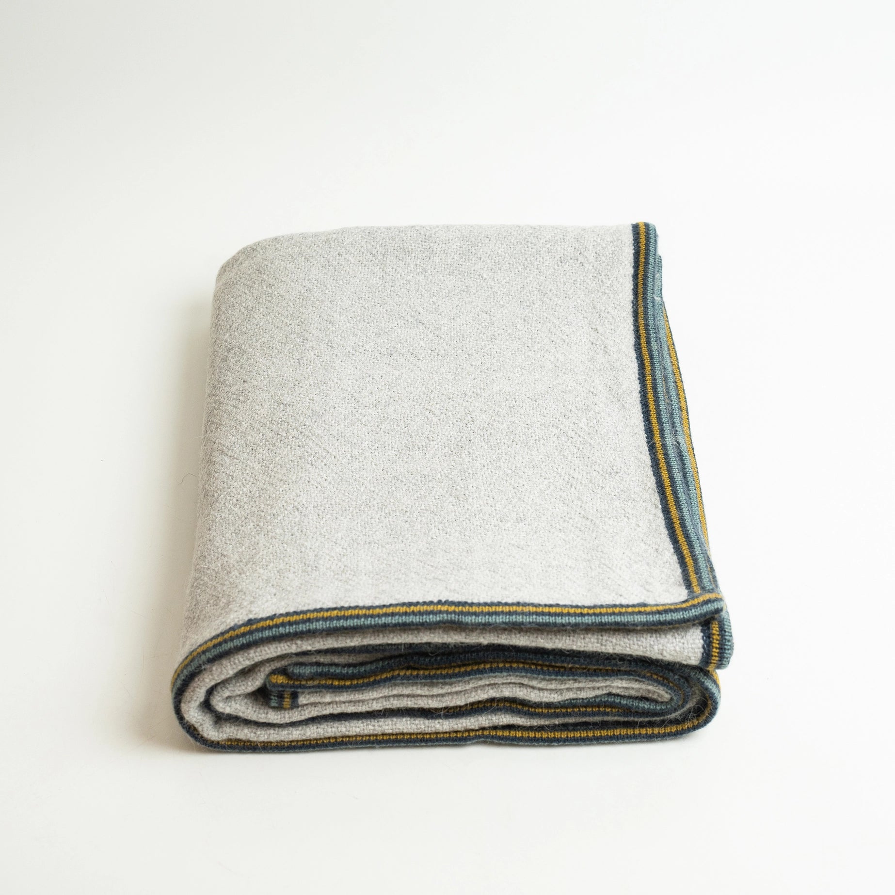 Alpaca wool blanket in gray with striped border, shown folded on white background