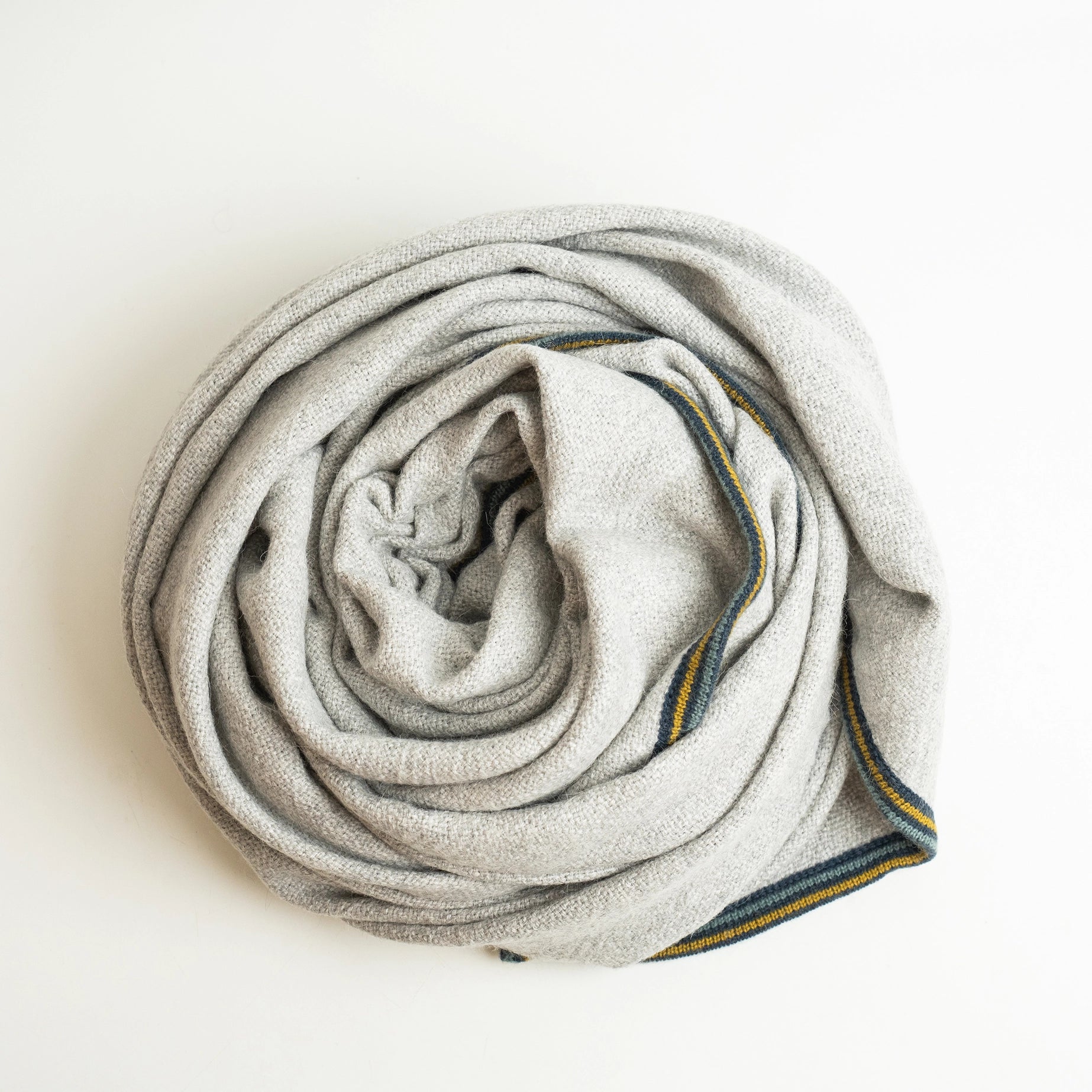 Alpaca wool blanket in gray with striped border, shown coiled up