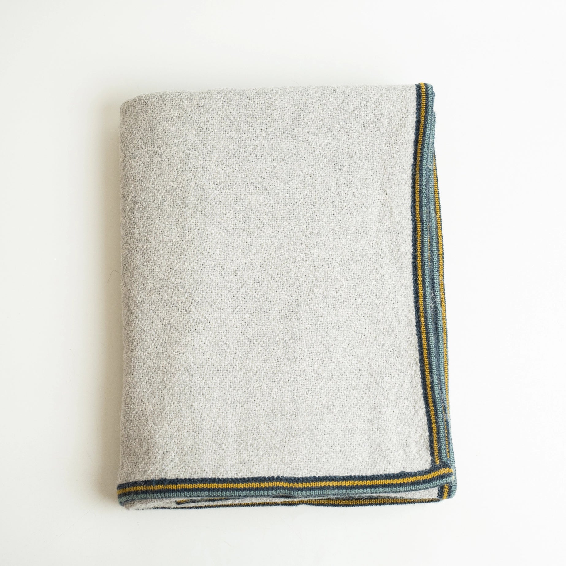 Alpaca wool blanket in gray with striped border, shown folded on white background