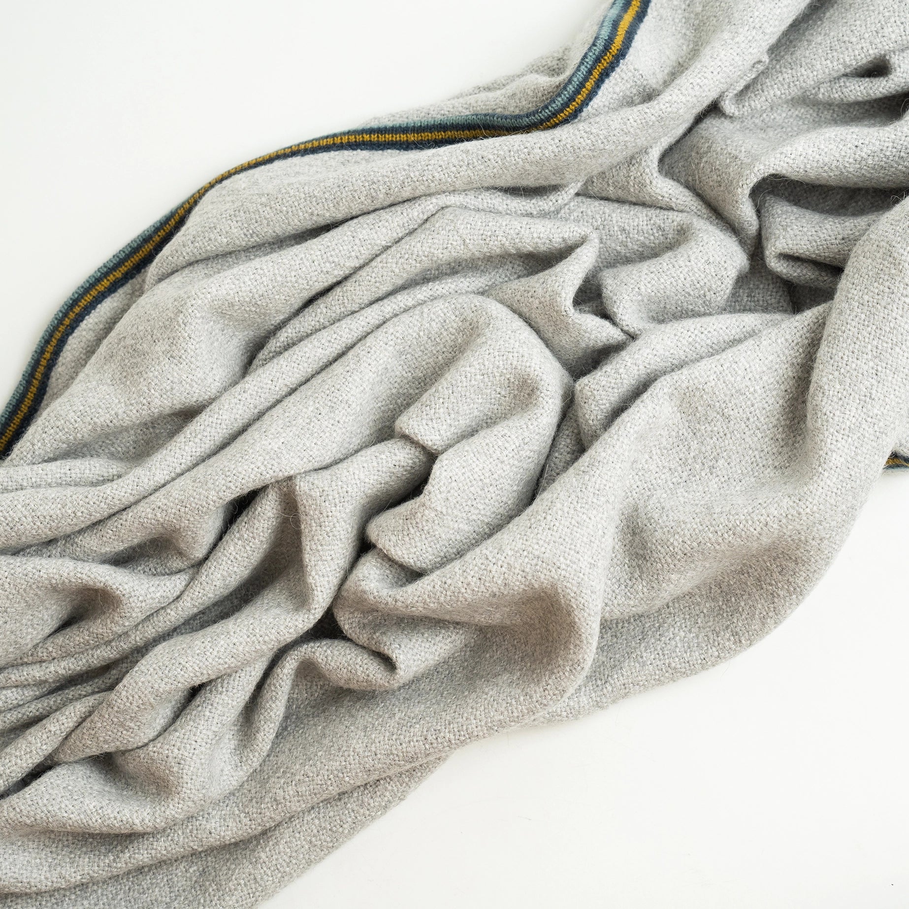 Alpaca wool blanket in gray with striped border, shown wrinkled up and cropped in