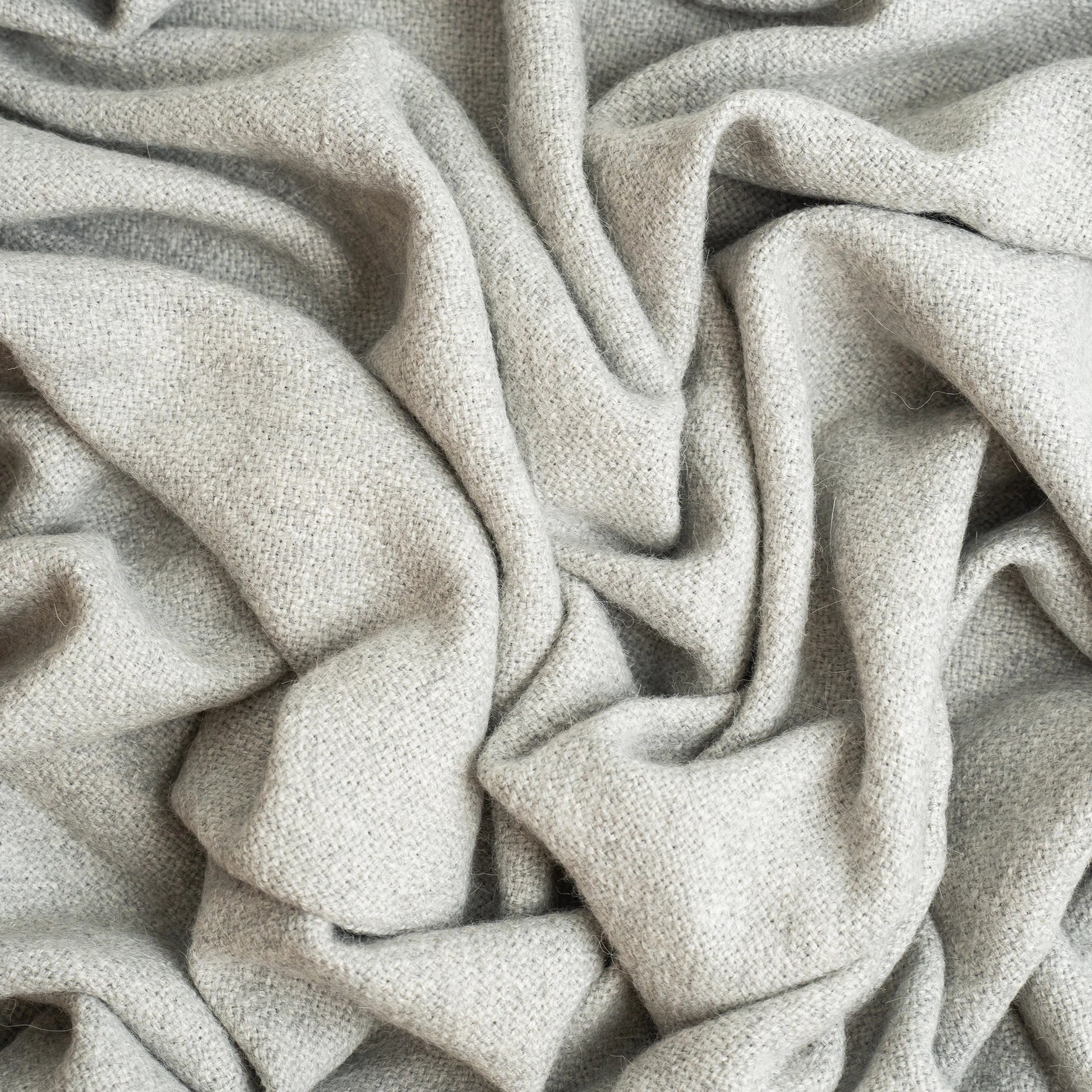 Alpaca wool blanket in gray with striped border, shown close up, with wrinkles, cropped in