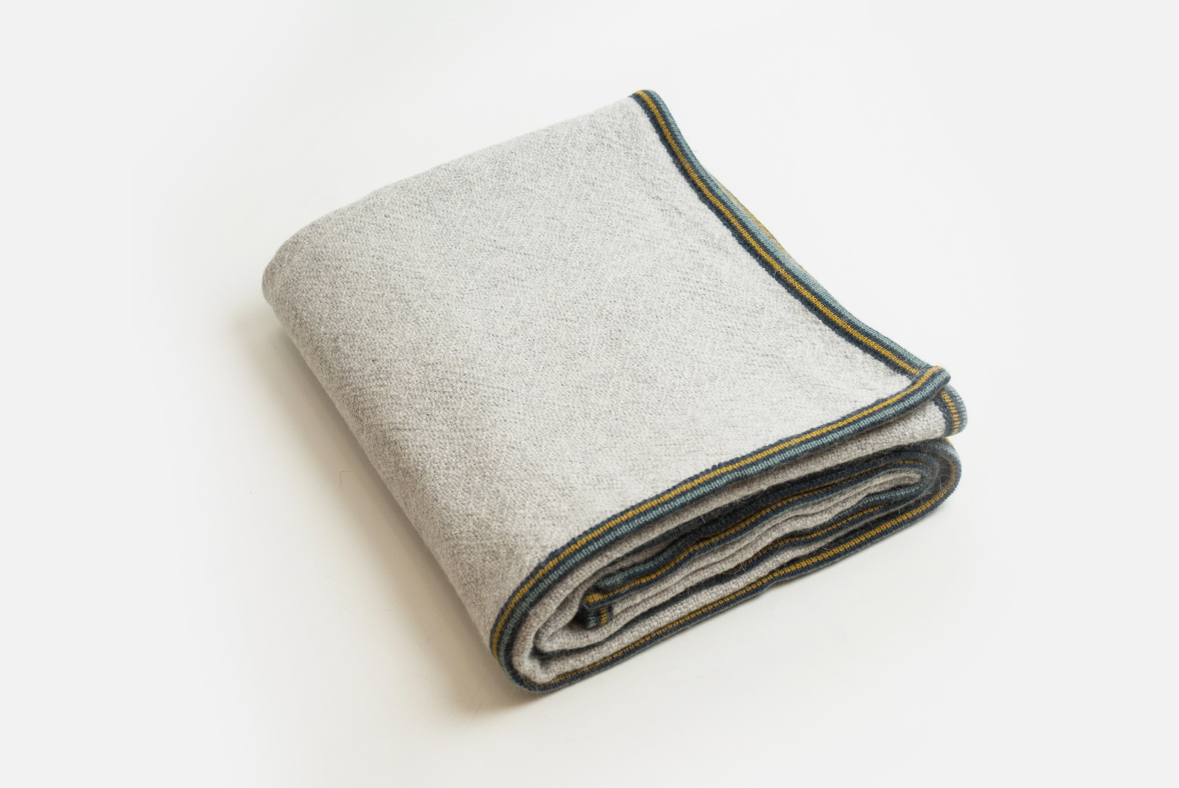 Alpaca wool blanket in gray with striped border, shown folded on white background