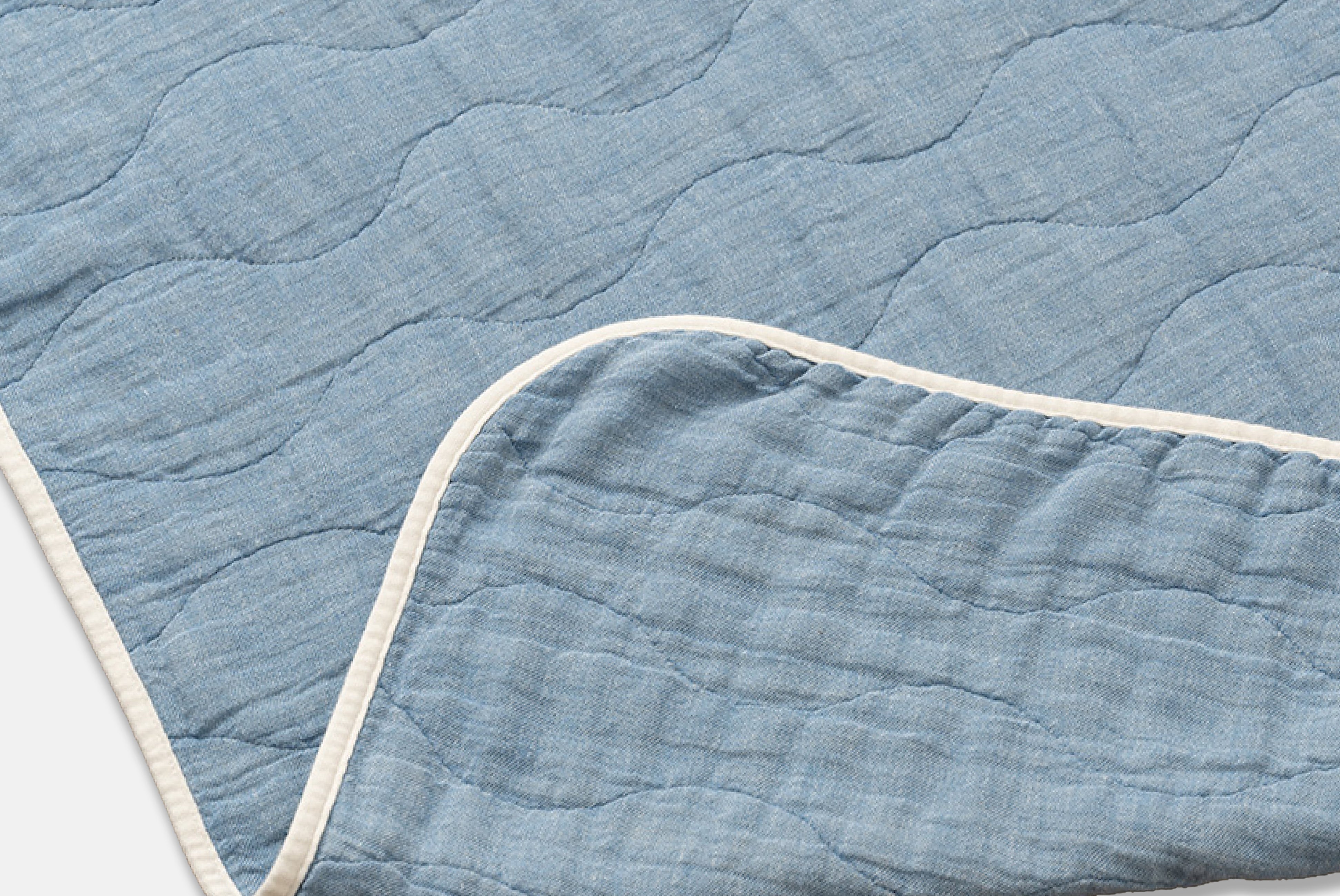 Close up of Japanese Cotton Blanket by Blanked, shown in Yurayura (blue), with corner folded, on white background