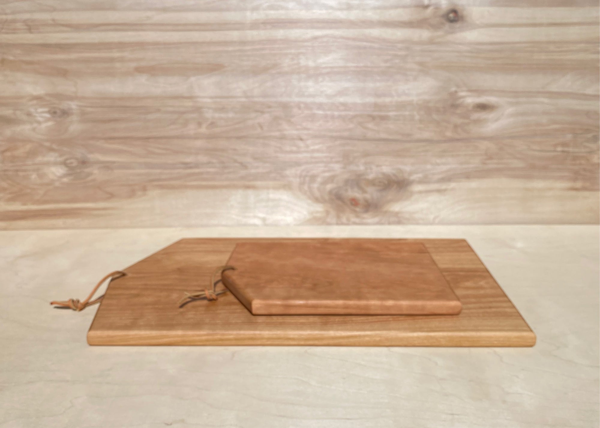 Asymmetric cutting board by Campover shown in sizes large and small in cherry wood