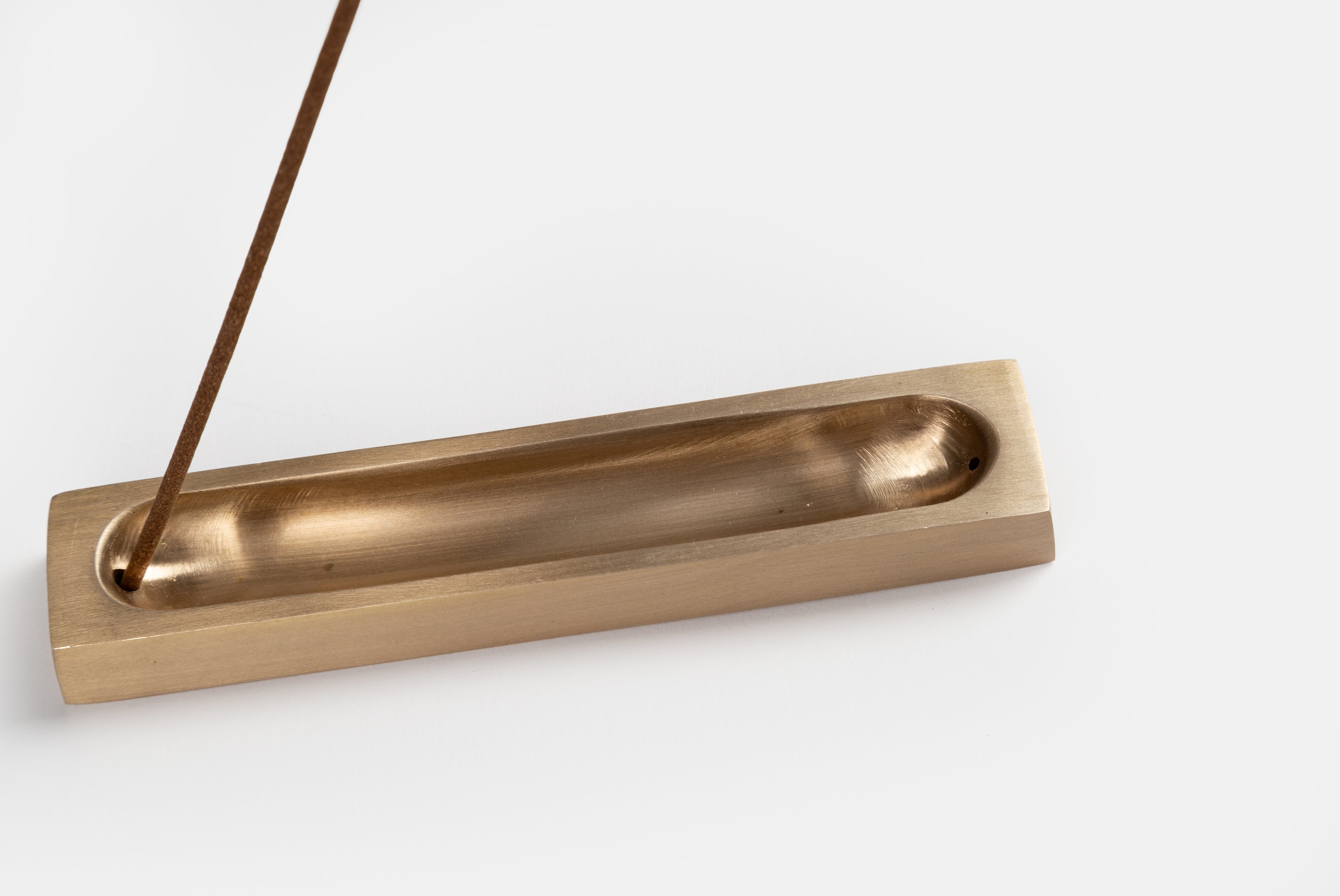 Fog Linen rectangular brass incense holder shown close up with a single incense stick on a white background