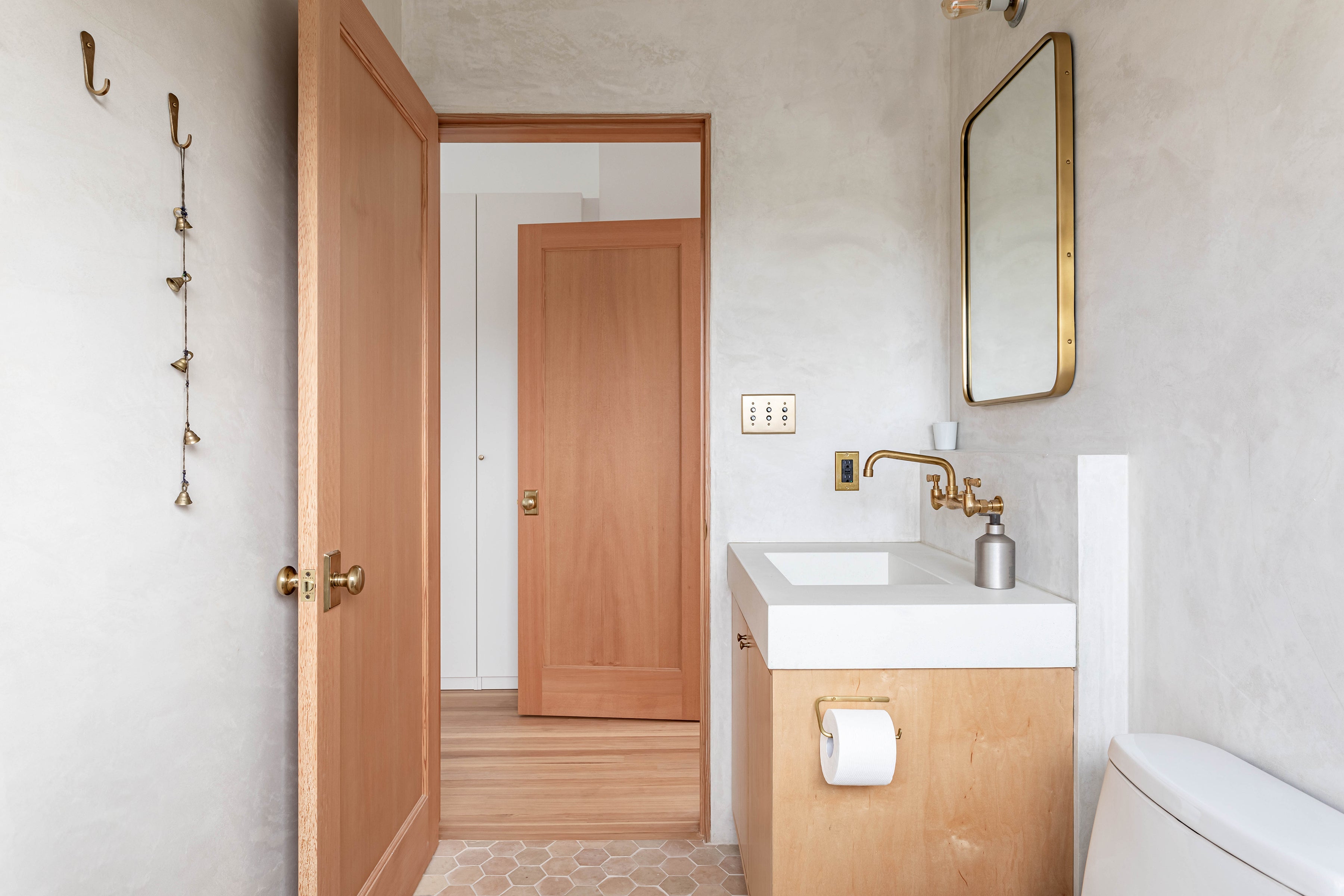 Fog Linen Brass Toilet Paper Holder shown on side of cabinet in Venice Beach bathroom