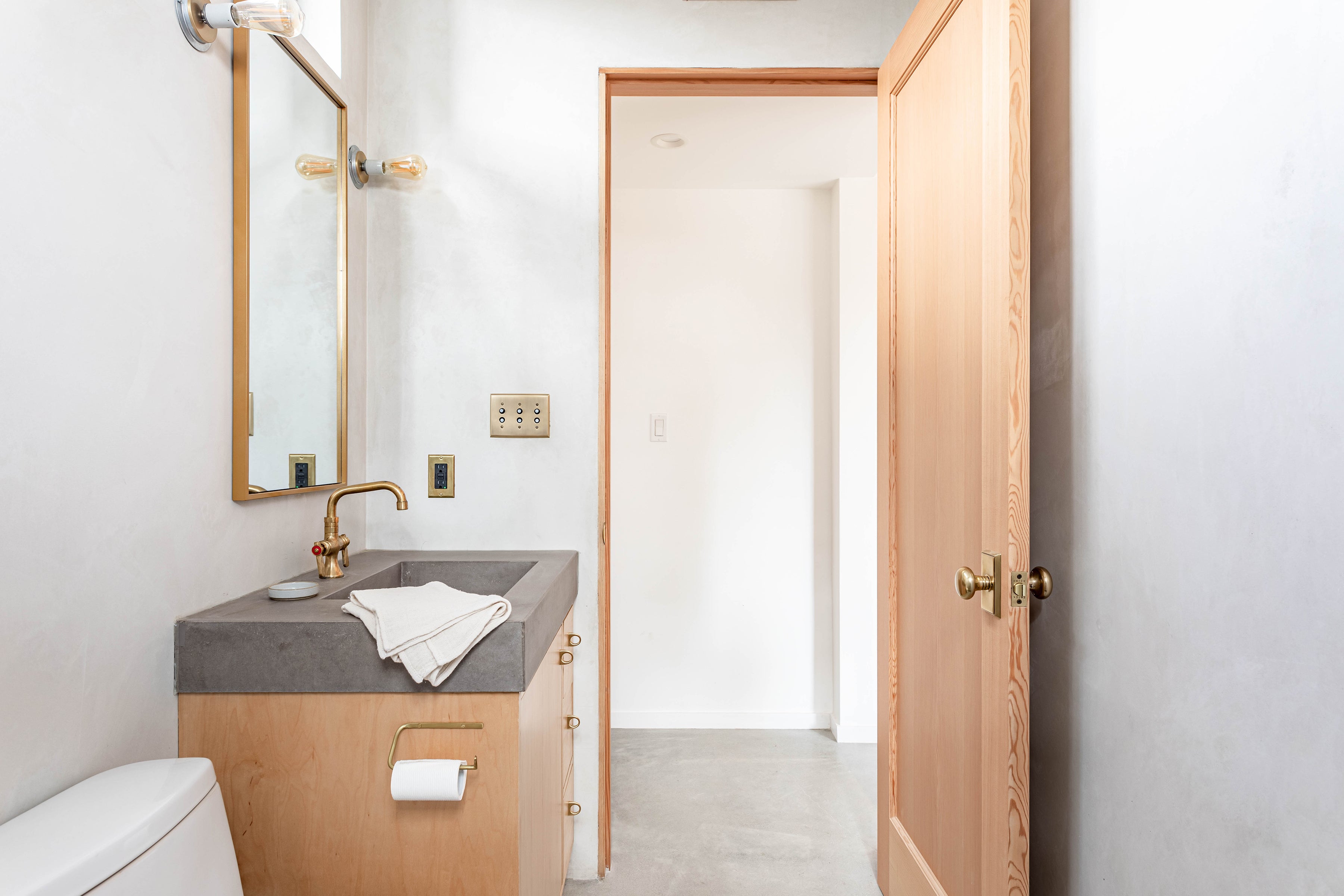 Fog Linen Brass Toilet Paper Holder mounted on side of cabinet in Venice Beach bathroom