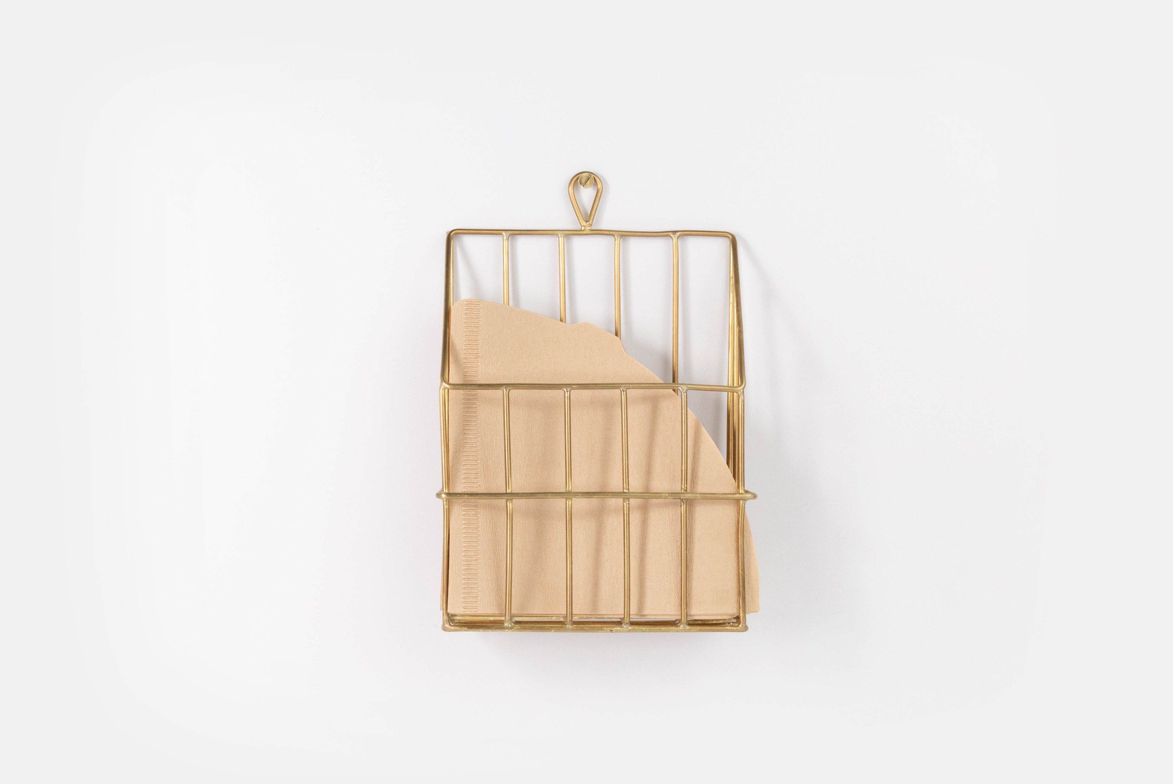 Brass Coffee Filter Holder by Fog Linen, shown hung on white background, holder filters