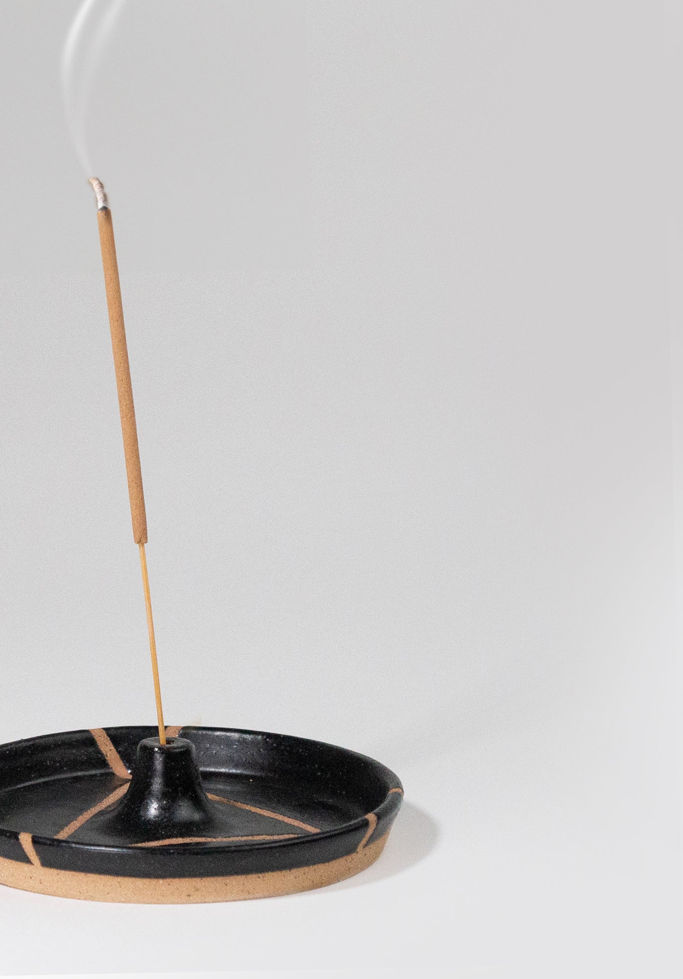 Cropped view of Ceramic Incense Holder by Fred James Pottery in matte black, shown with incense burning on white background