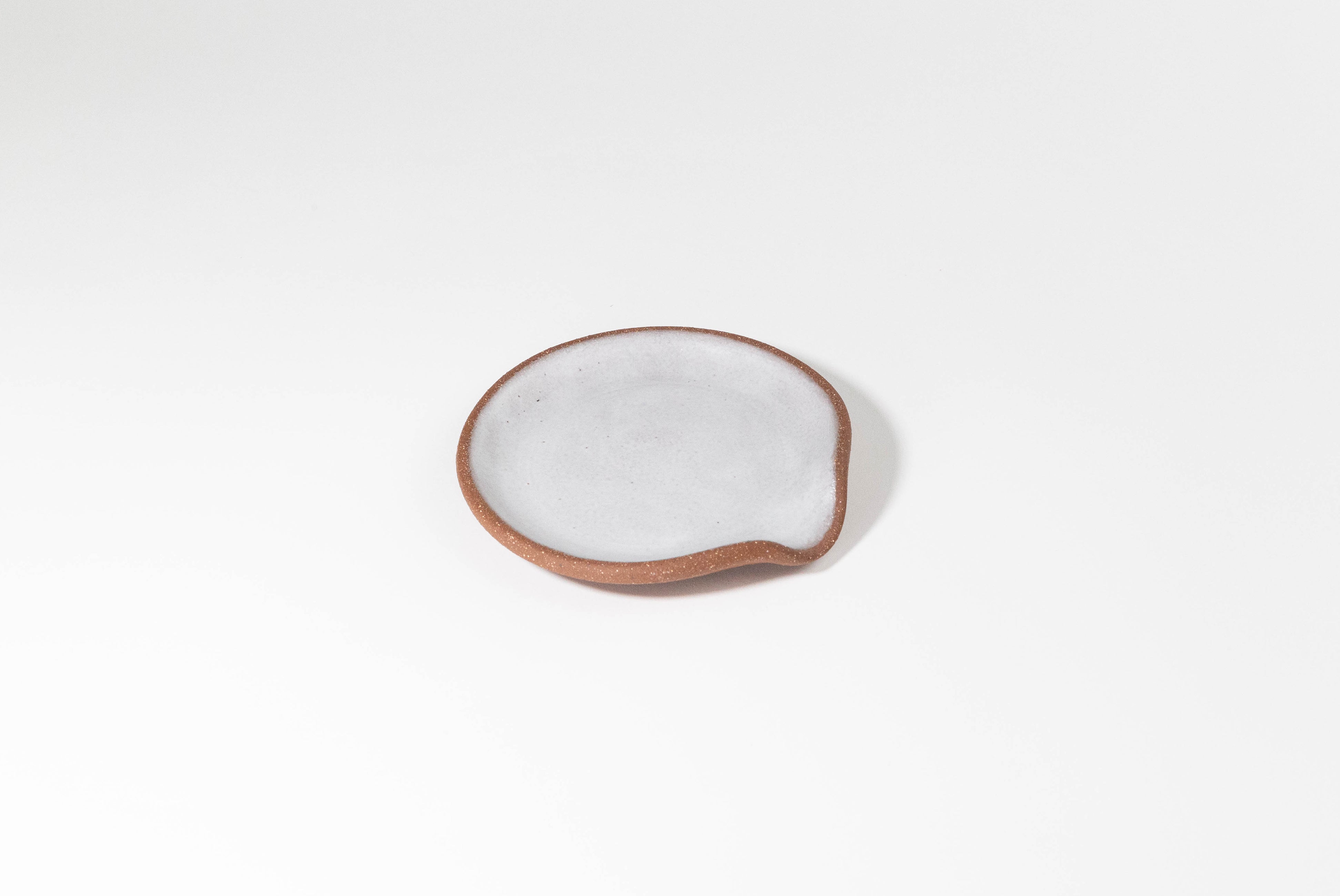 Ceramic Spoon Rest by Fred James Pottery in textured brown clay and matte white glaze, shown on white background