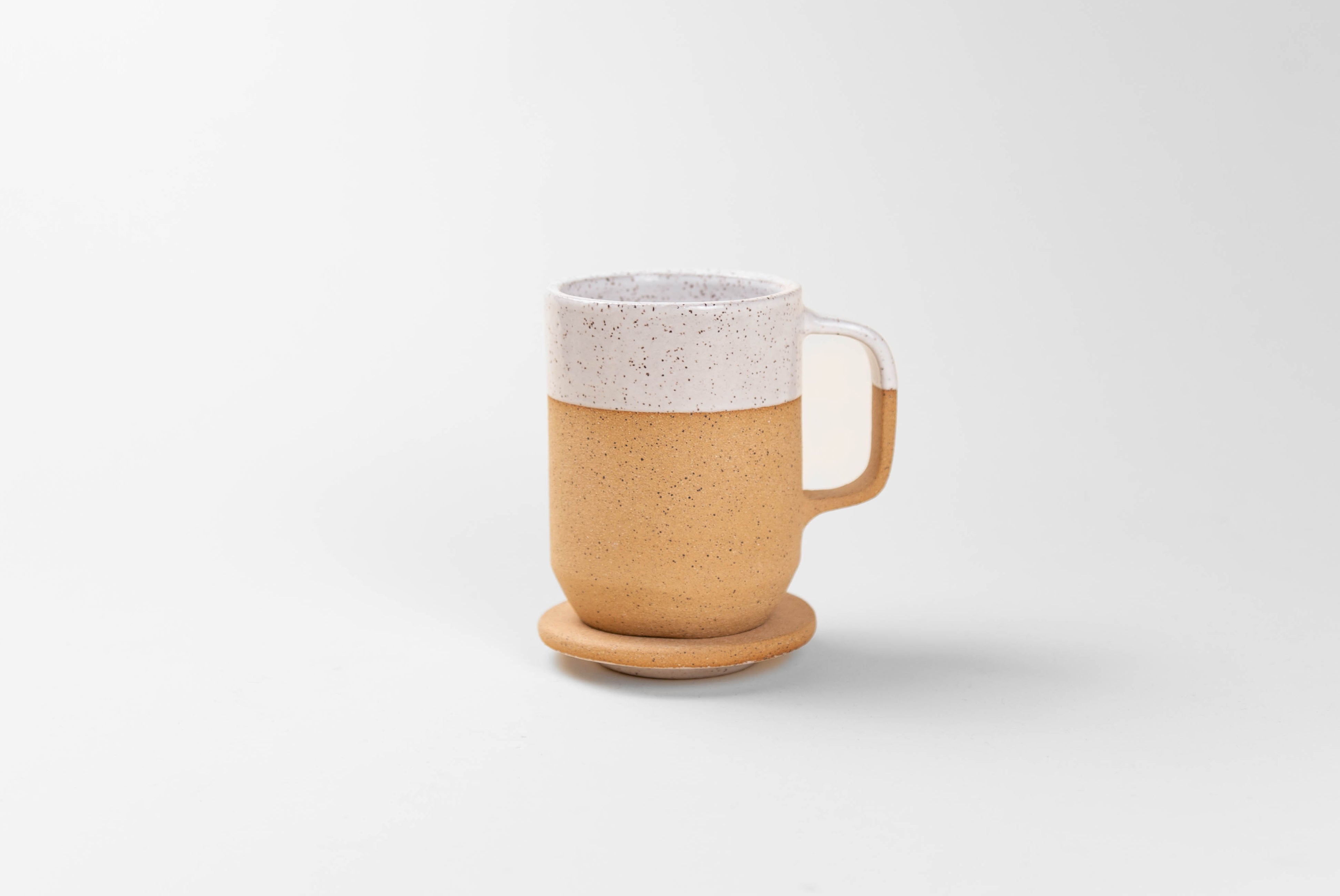 Ceramic Tea Mug with Lid in natural textured clay with speckled matte white glaze on top half, shown with lid being used as coaster, on white background