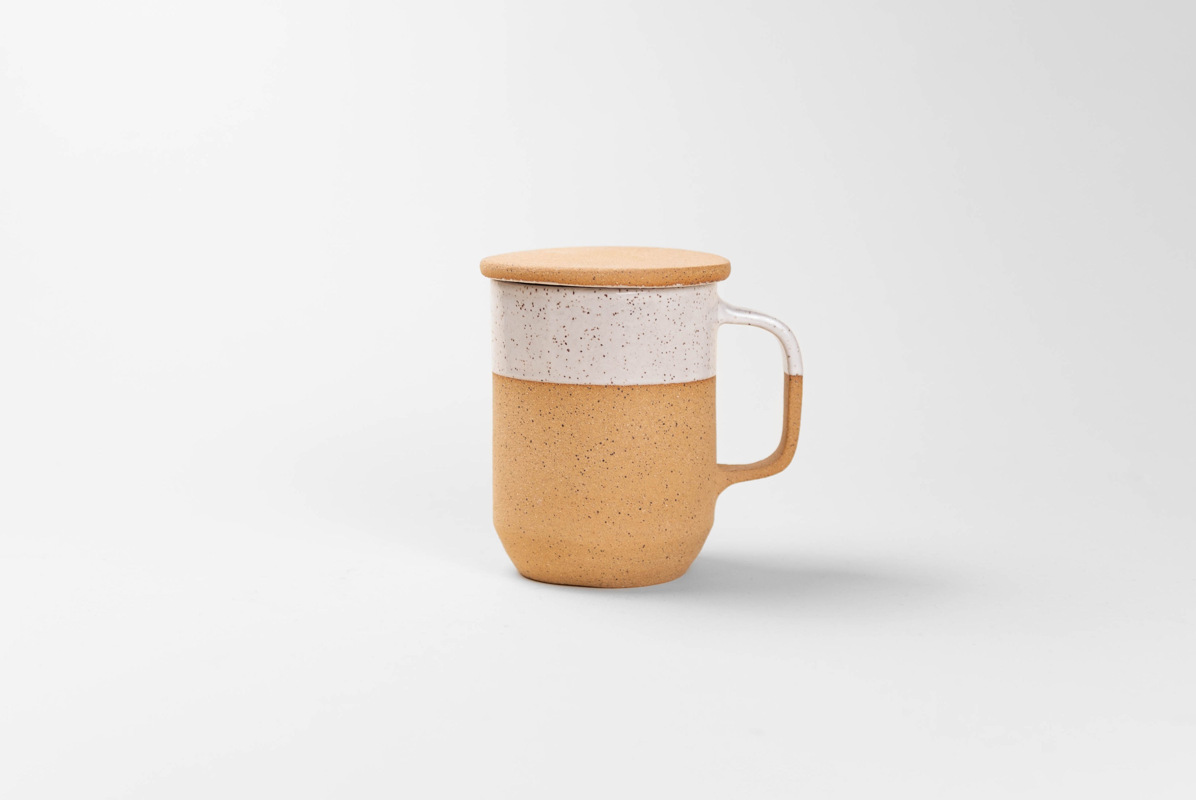 Ceramic Tea Mug with Lid in natural textured clay with speckled matte white glaze on top half, shown with lid on to keep tea hot, on white background