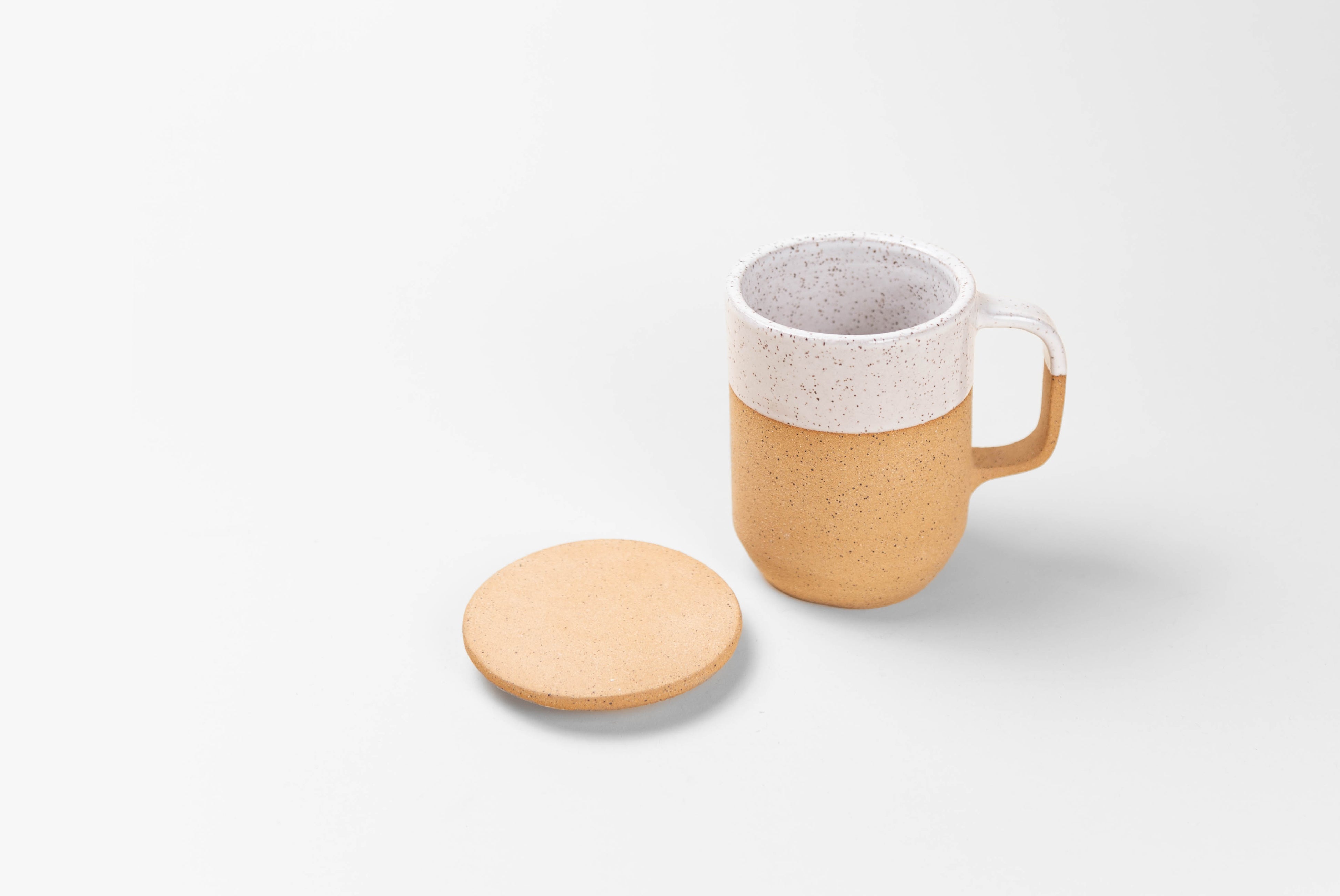 Ceramic Tea Mug with Lid in natural textured clay with speckled matte white glaze on top half, shown with lid resting on surface beside, on white background