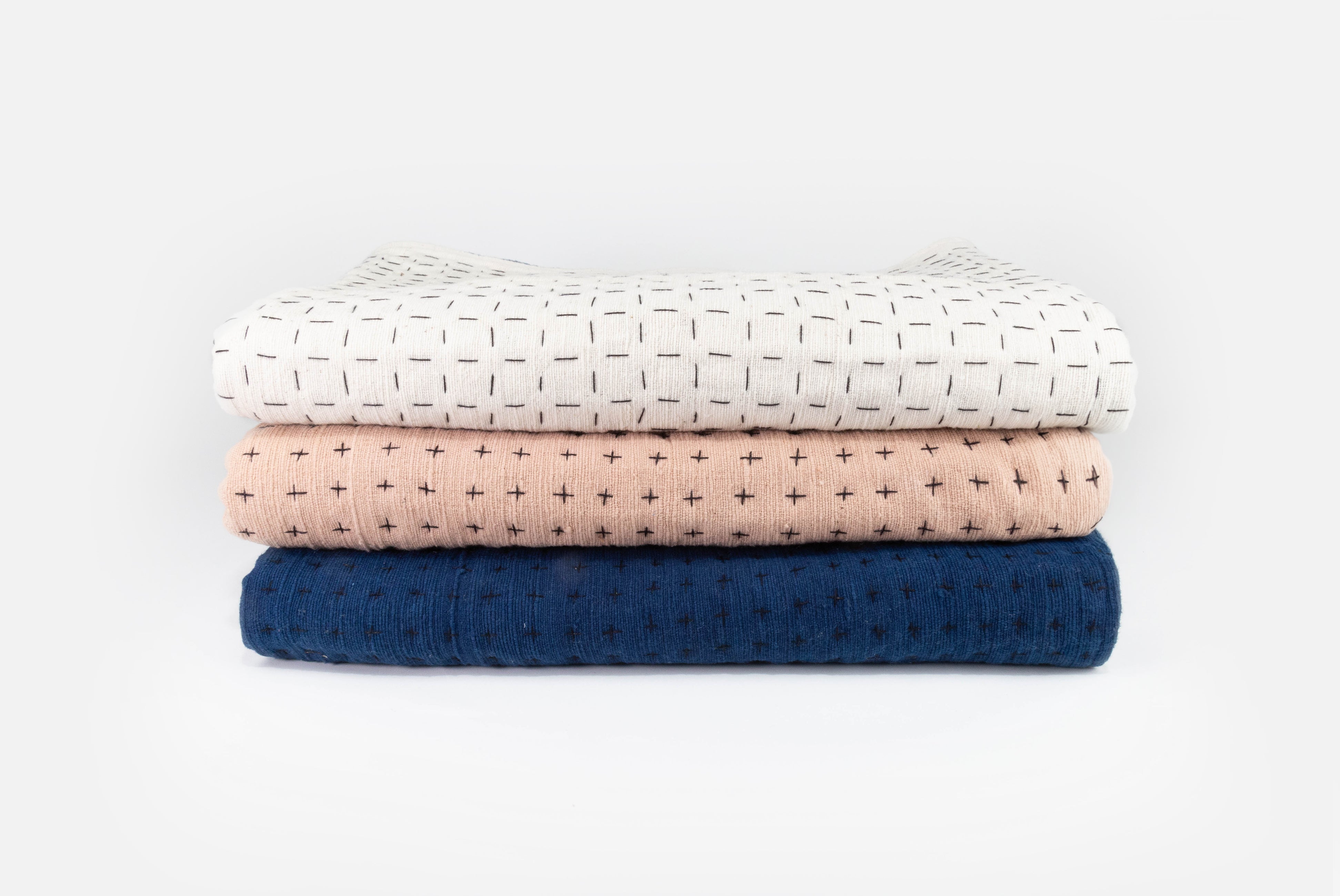 Handmade blanket by Happy French Gang, shown in folded stack of three colors