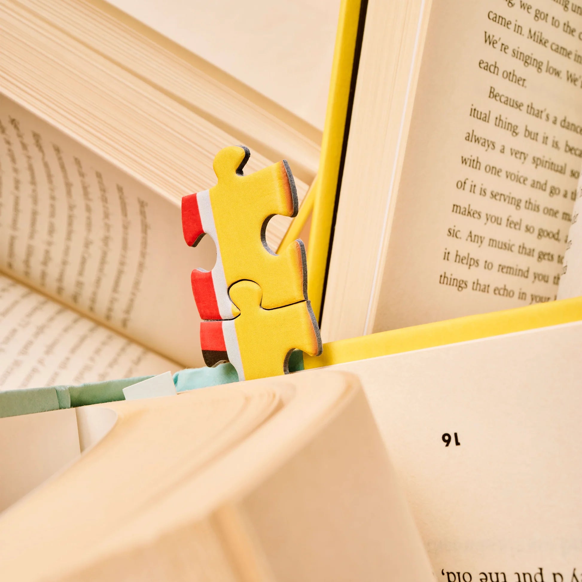 Close up of puzzle pieces from Bookworm Puzzle by Piecework Puzzles with open books in the background