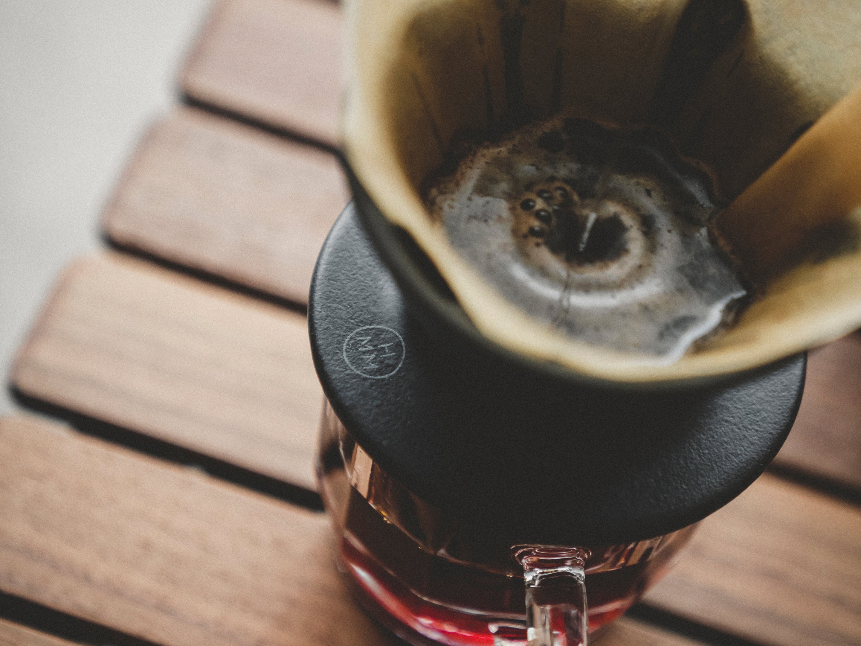 Close up of Patio Ceramic Coffee Dripper by HMM in matte black, shown with coffee and filter