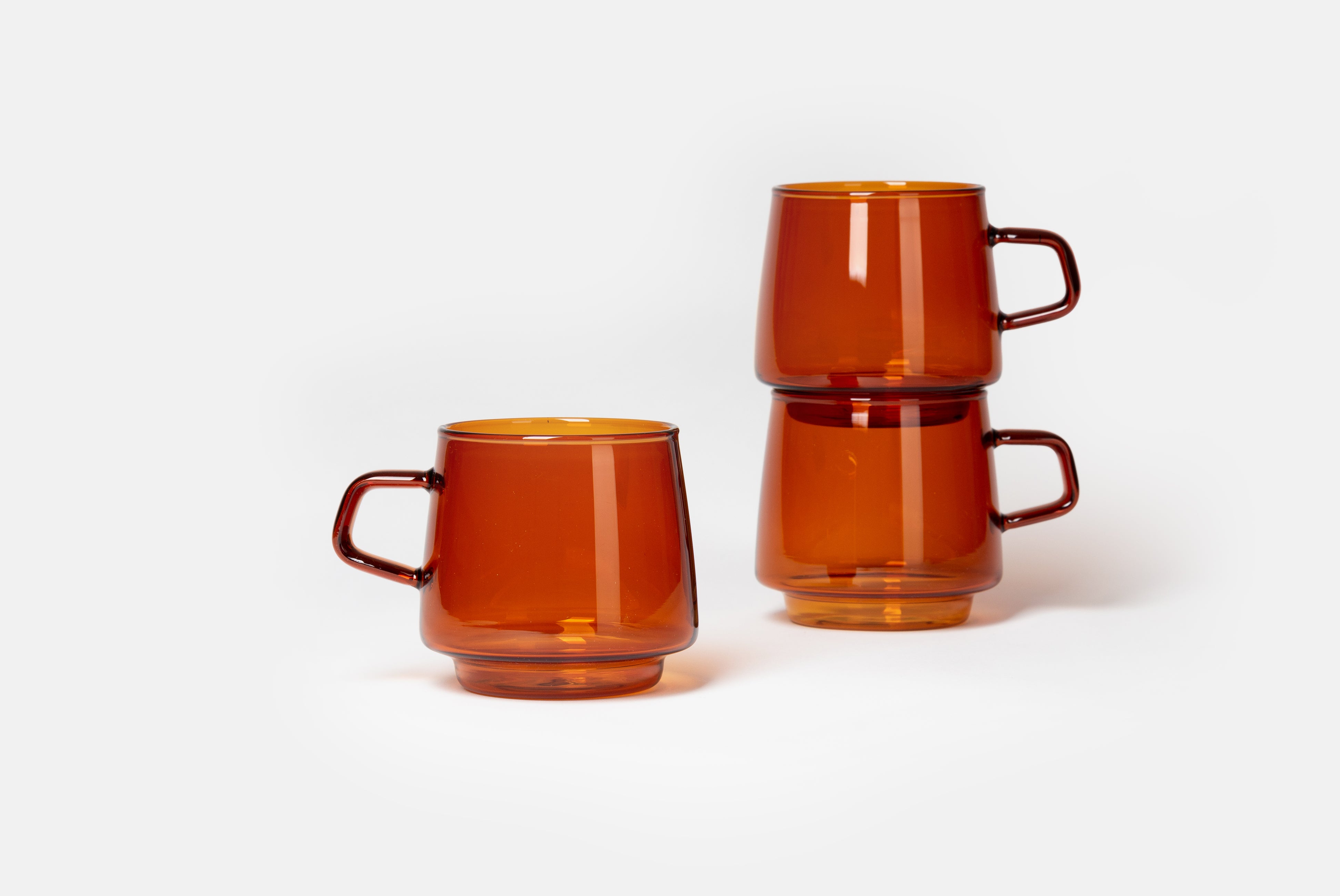 Sepia Mug by Kinto shown in Amber color, in group of three on white background