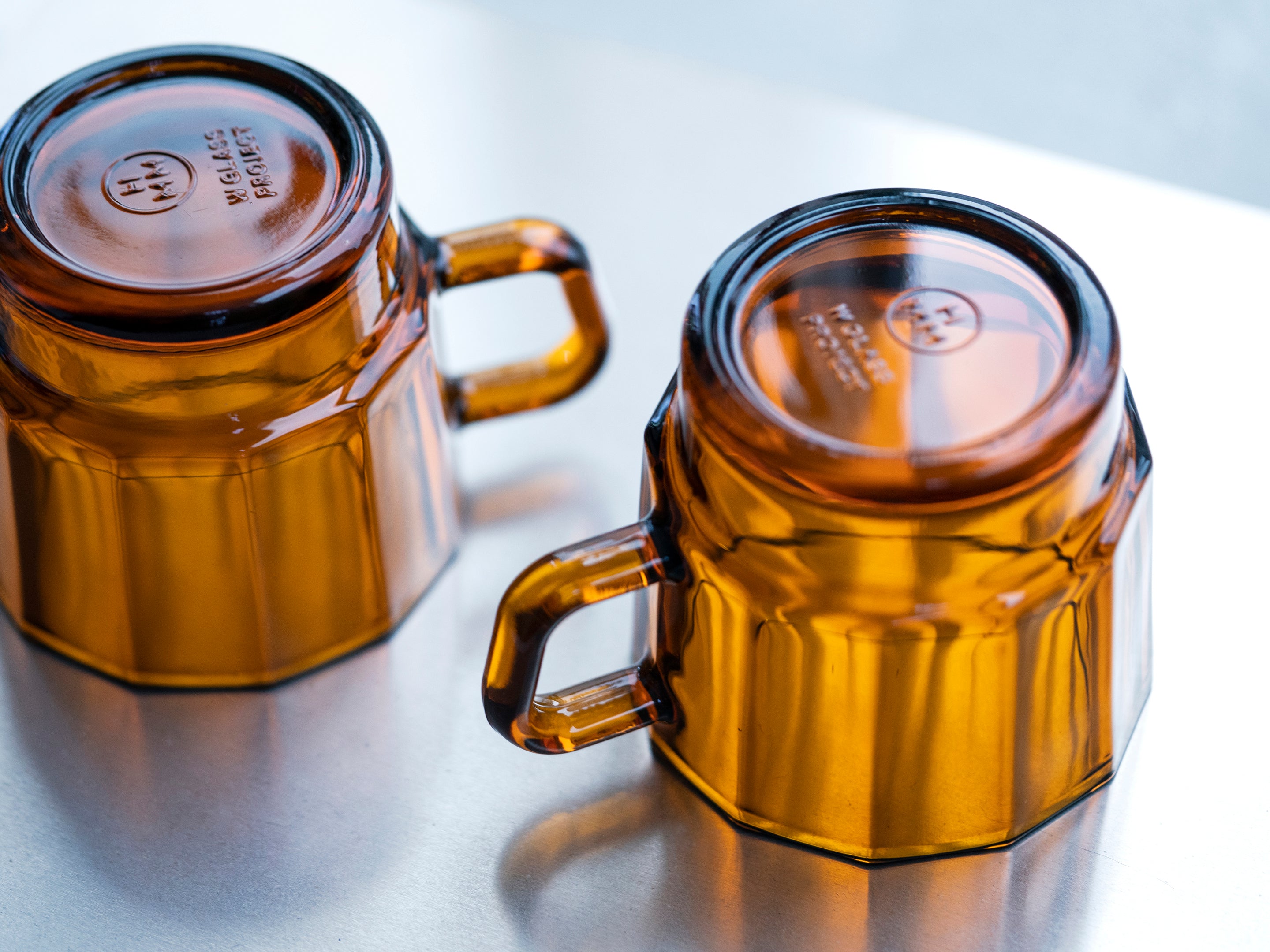 W Glass by HMM shown as a pair in amber color, upside down on surface