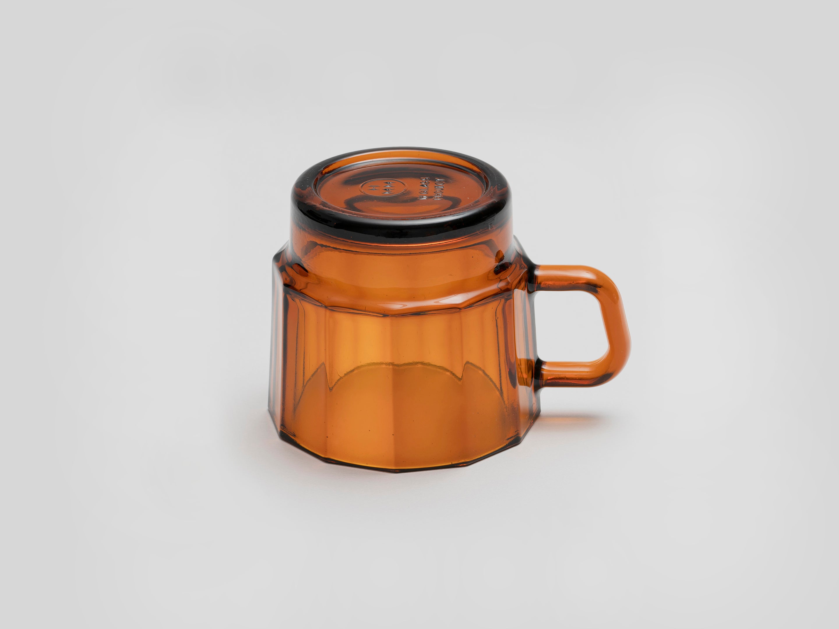 W Glass by HMM shown in amber color, resting upside down, on white background