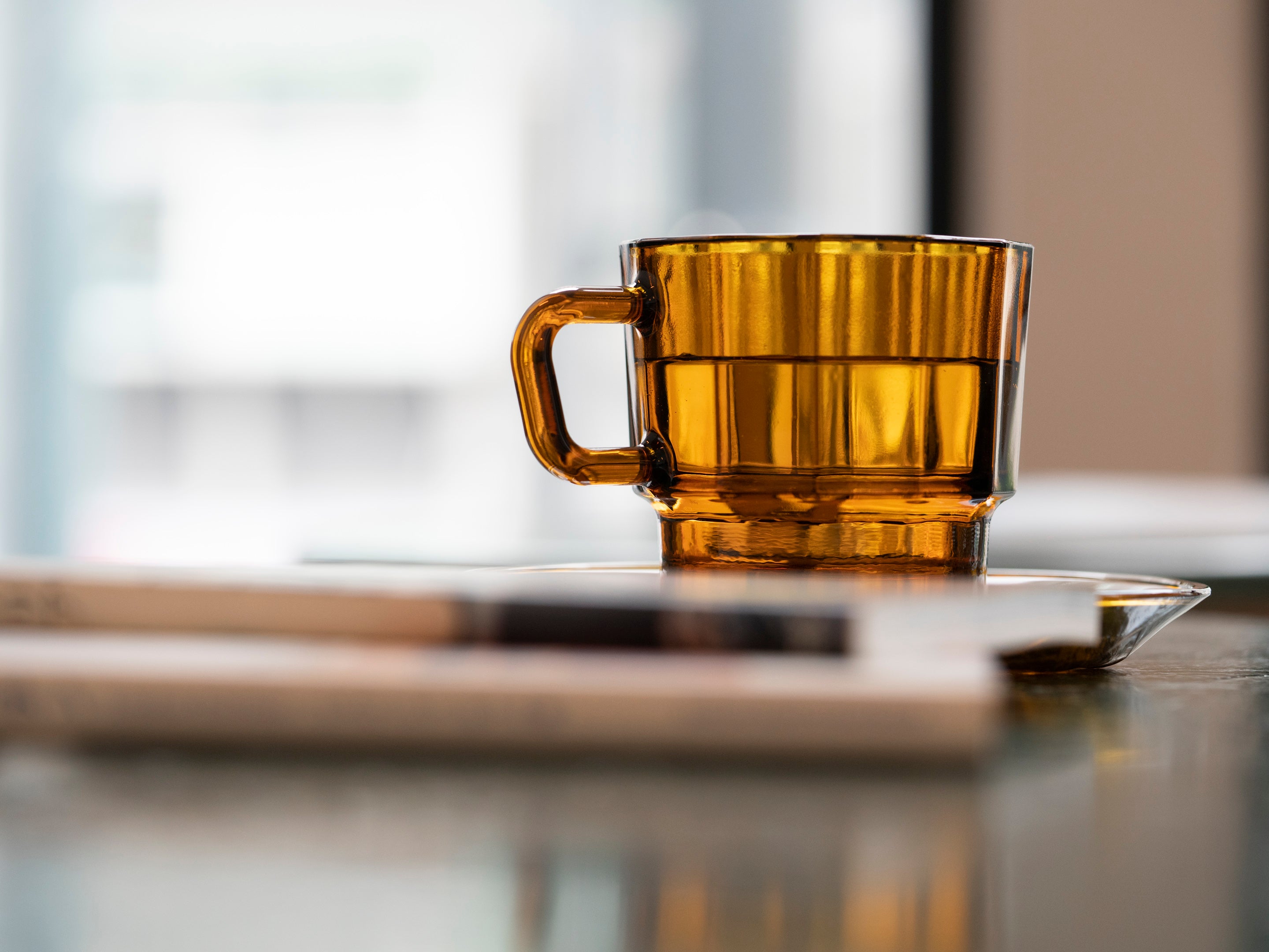 W Glass by HMM shown in amber with water on desk surface
