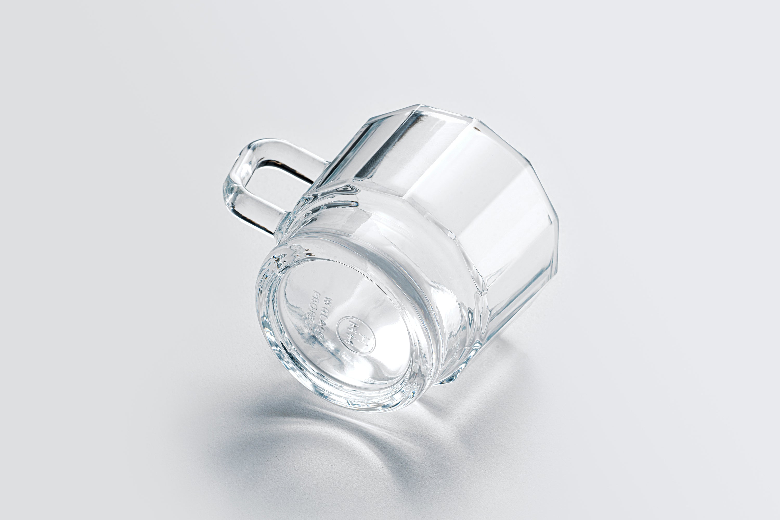 W Glass by HMM shown in clear, resting on its side with the bottom visible, on white background