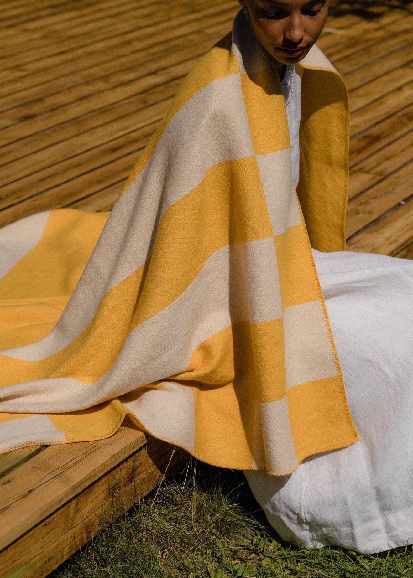Aspen Throw Blanket shown draped over a person sitting outdoors on a large deck
