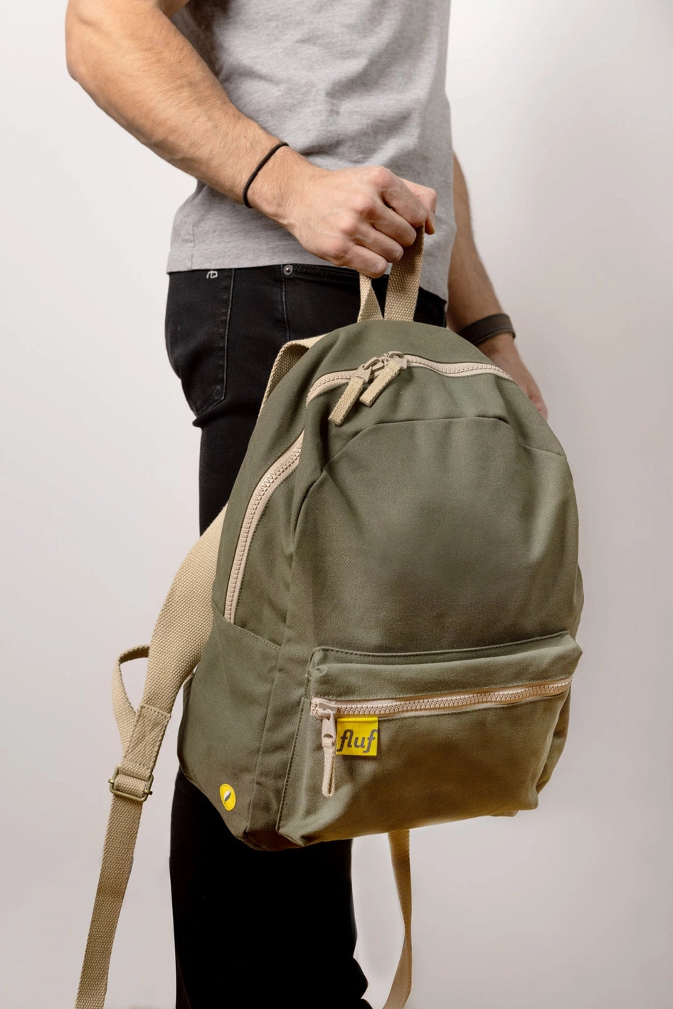 Fluf Organic B Pack Backpack shown in Dark Olive held by person with right hand