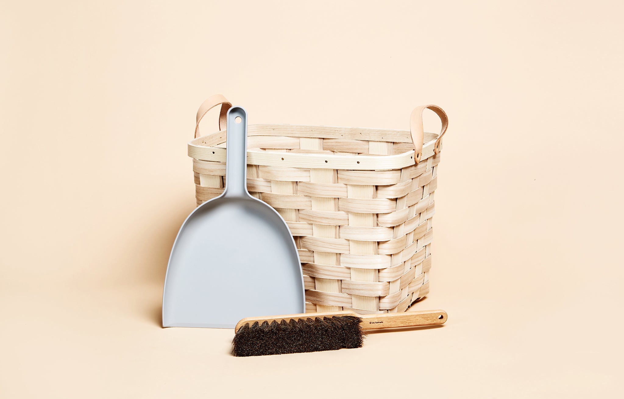 Iris Hantverk Dustpan & Brush Set shown with woven basket on light peach background