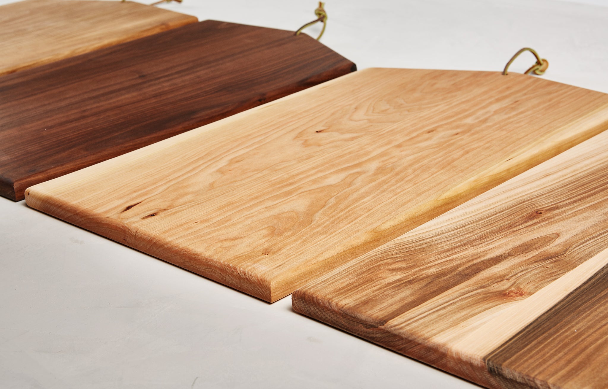 Asymmetric Wood Cutting Board by Campover shown in four wood options including cherry, walnut, maple, and two-tone maple