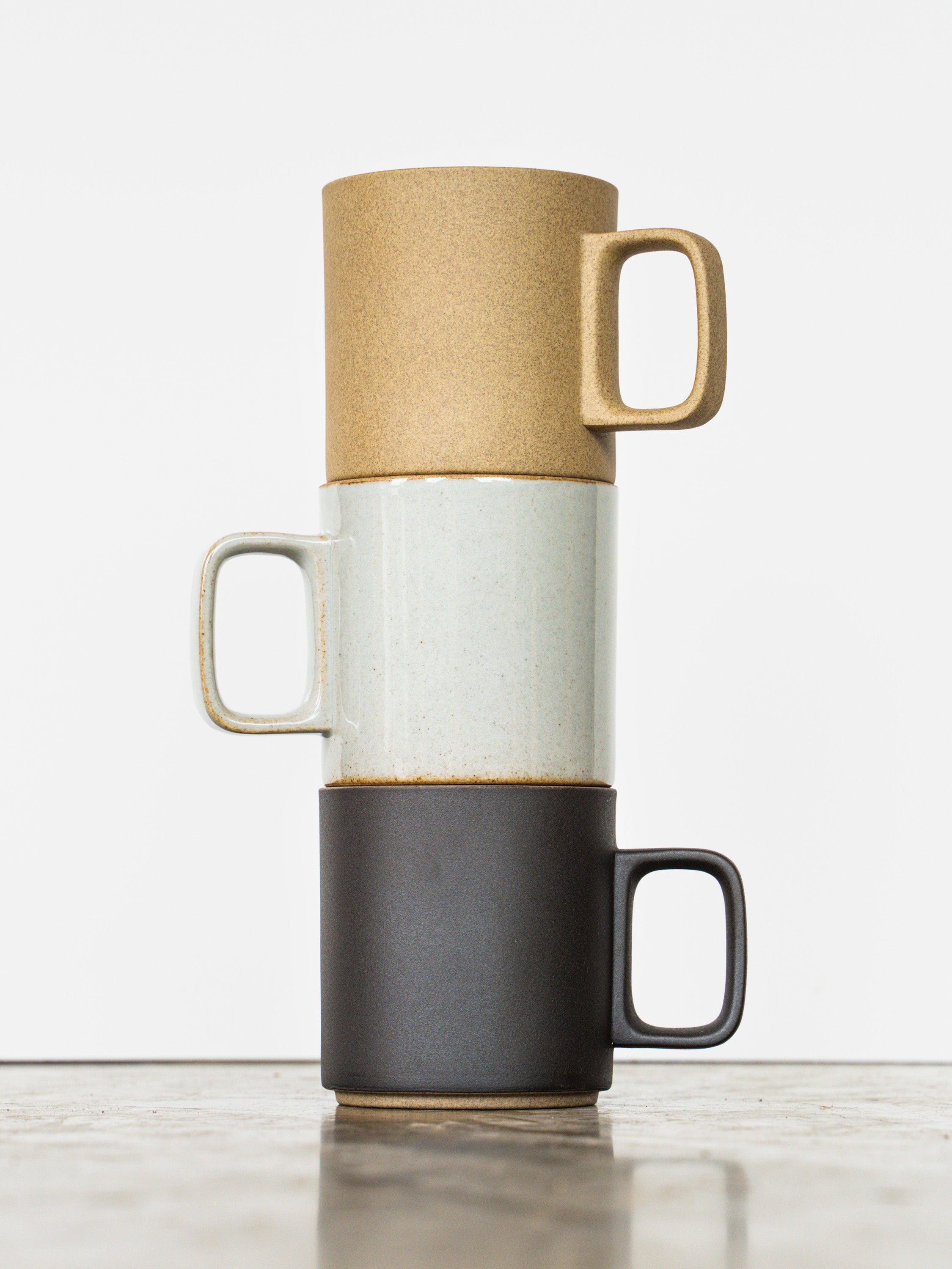 Hasami Mugs in medium size in natural, gloss gray, and matte black shown stacked