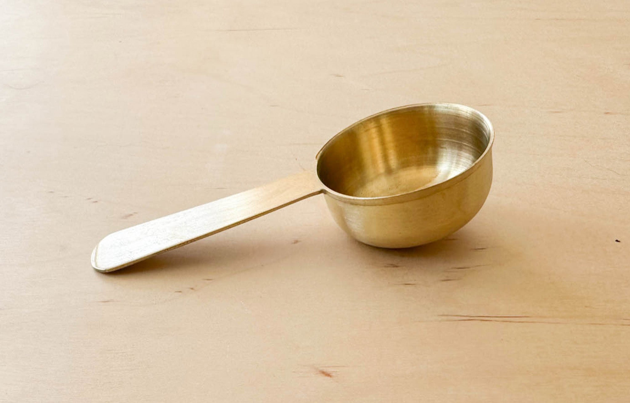 Fog Linen Brass Scoop zoomed-in closeup of side angle on wood surface