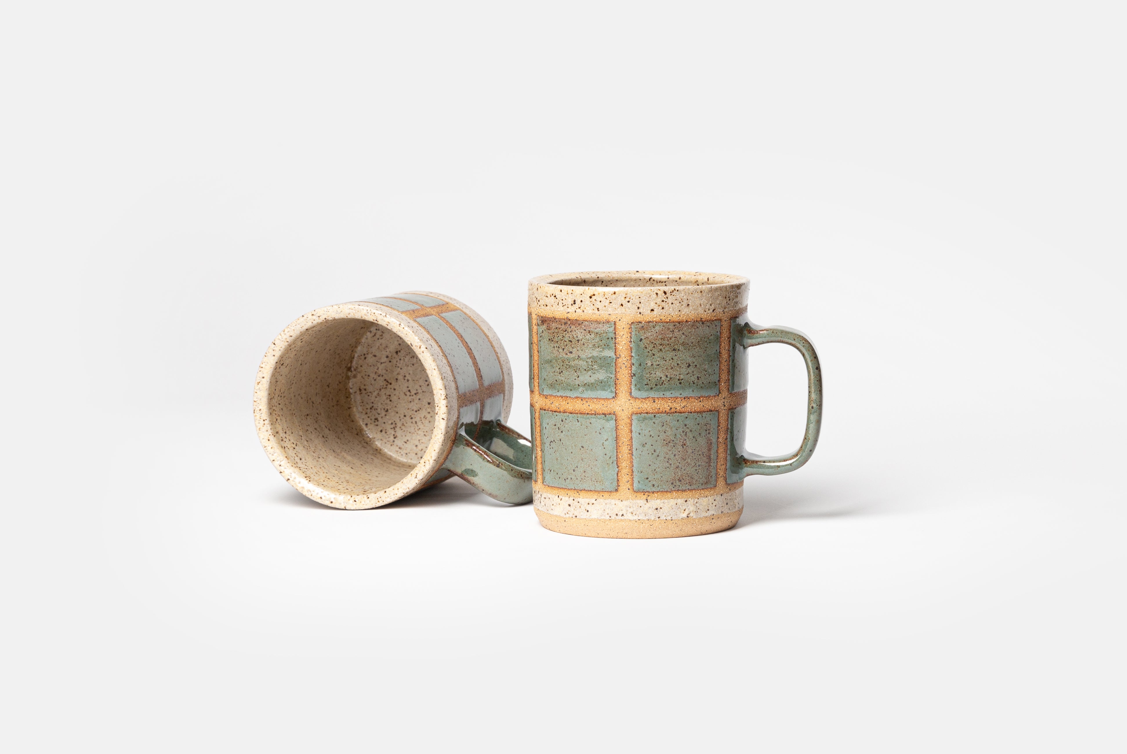 Two Ceramic Camp Mugs by Campover in collaboration with Fred James Pottery, shown with one standing and one laying flat, on white background