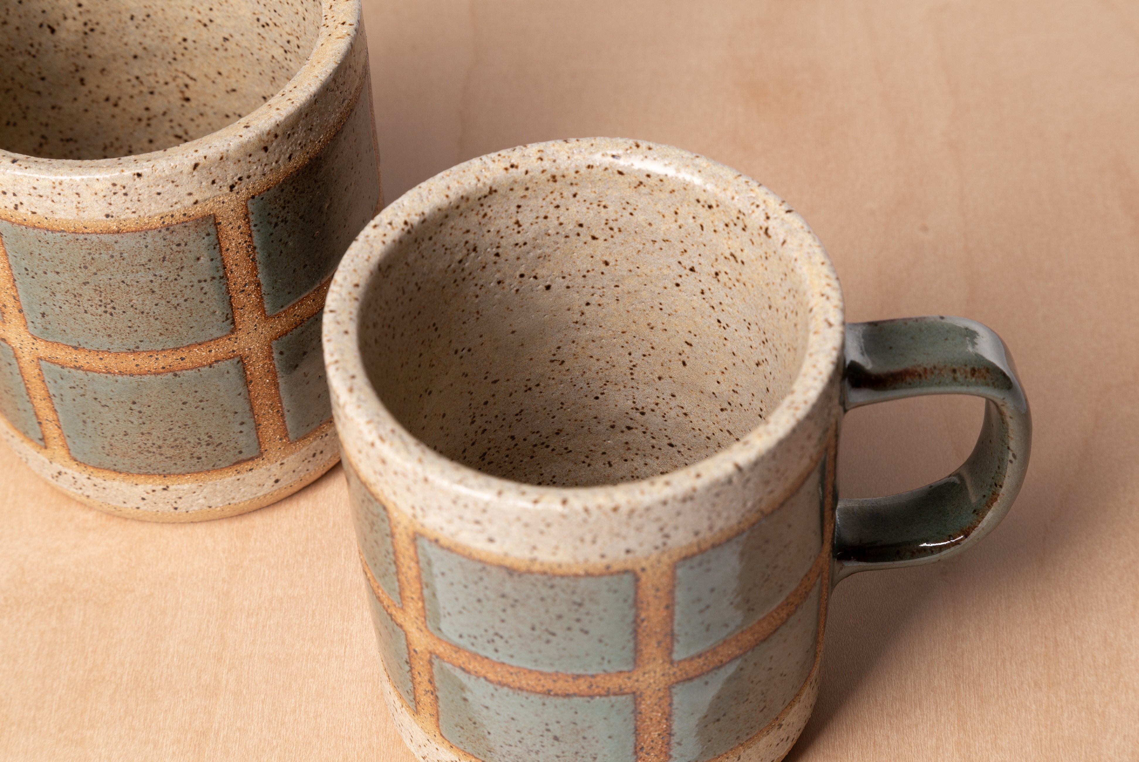 Two Ceramic Camp Mugs by Campover in collaboration with Fred James Pottery, shown close up, on wood surface