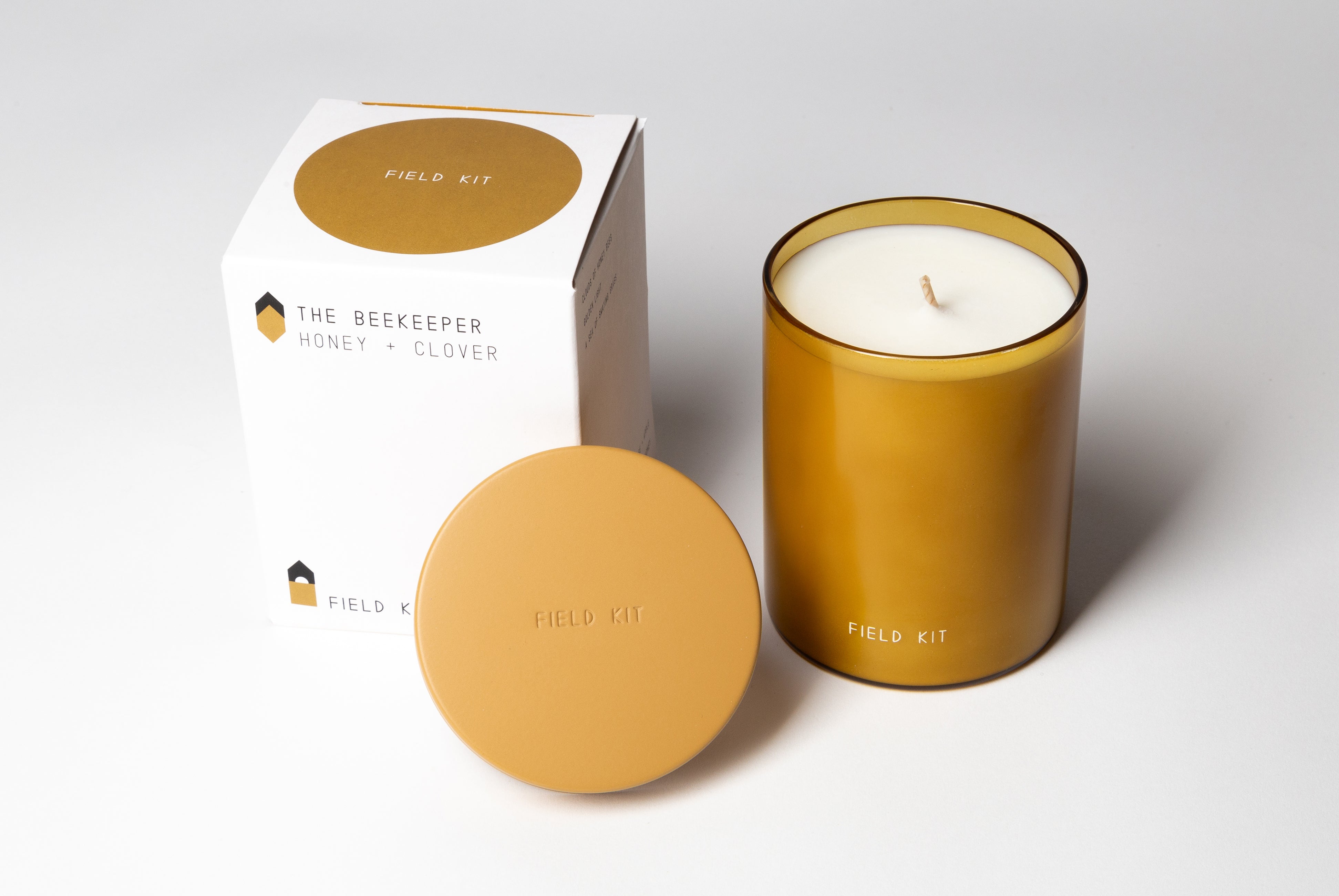 The Beekeeper Candle by Field Kit, shown with box and top off, on white background