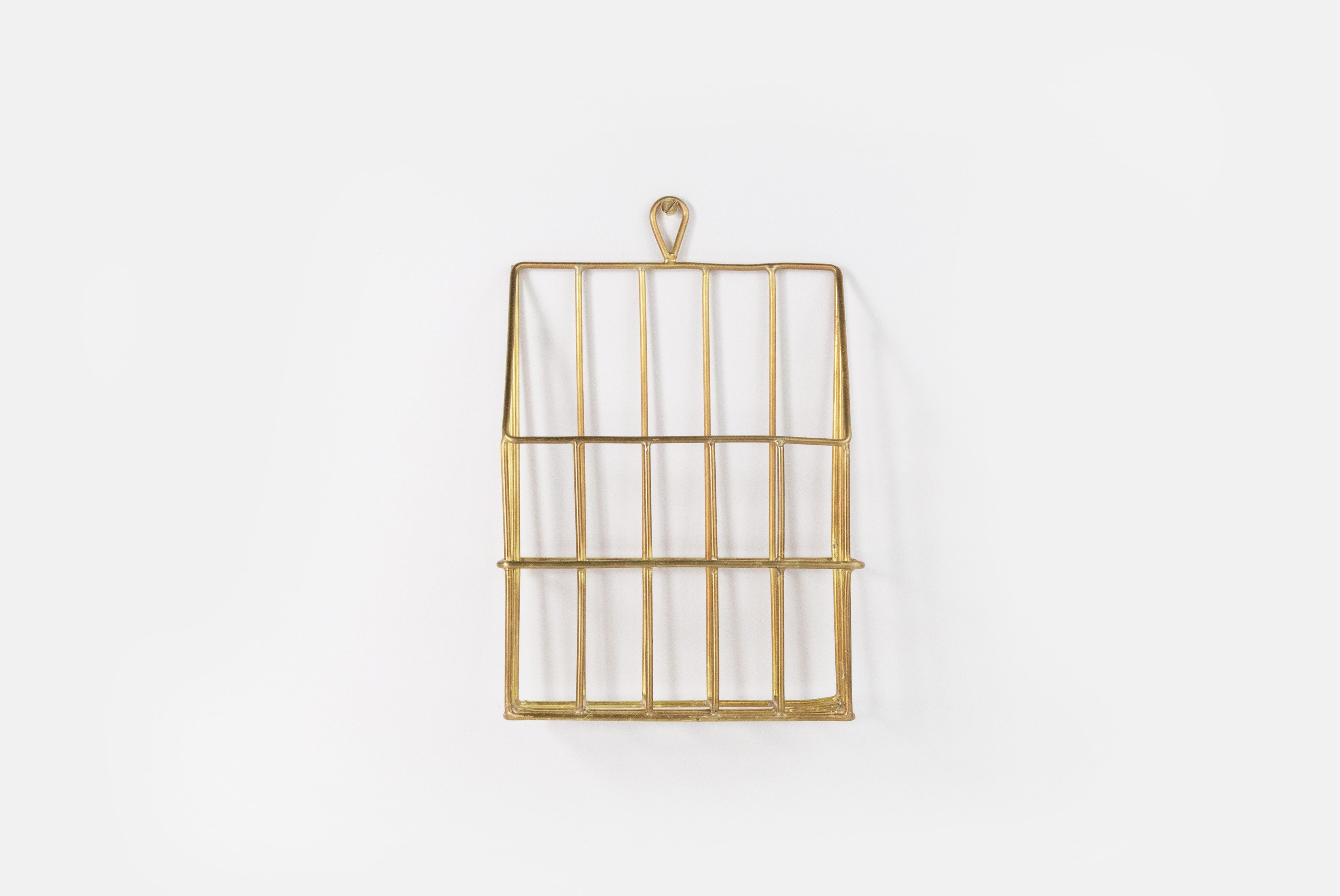 Brass Coffee Filter Holder by Fog Linen, shown hung on white wall