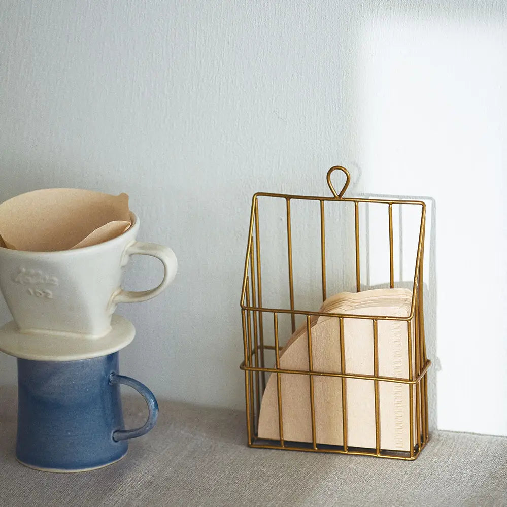 Brass Coffee Filter Holder by Fog Linen shown rest on concrete countertop